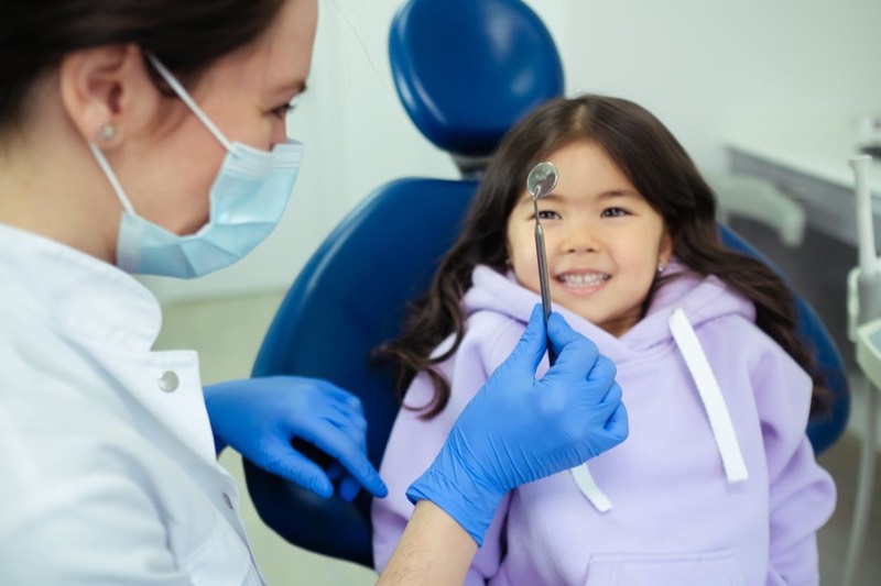 Niña sonriendo en el sillón dental durante su revisión