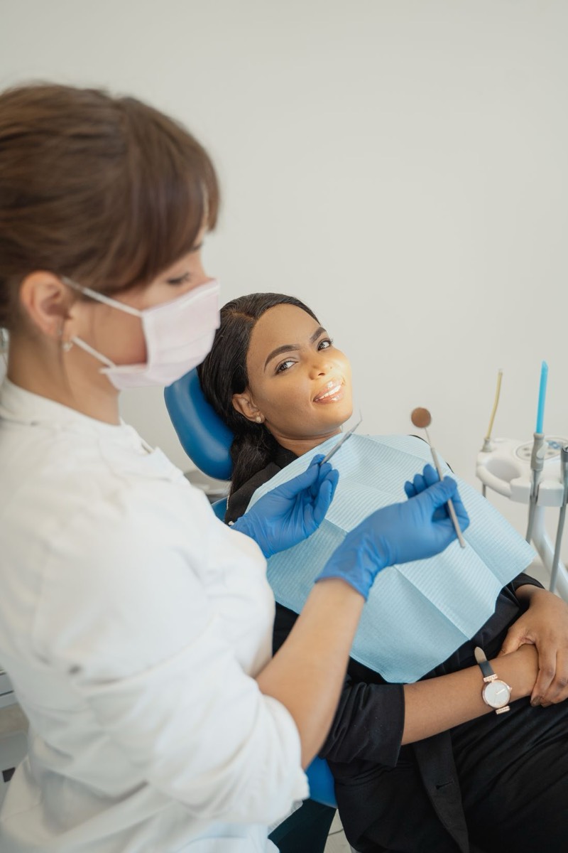 Odontóloga y paciente sonriendo durante una limpieza dental